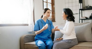 Evde geçirdiği felçten sonra yaşlı kadına ilaç veren genç hemşire.