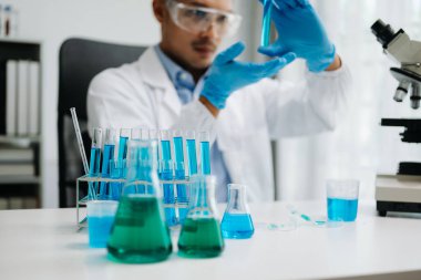 Erkek biyoteknoloji uzmanı laboratuvarda yeni kimyasal maddeler test ediyor. Biyokimyasal örnekleri analiz eden mikro pipetlerle tıp için ileri bilim kimya laboratuvarı.