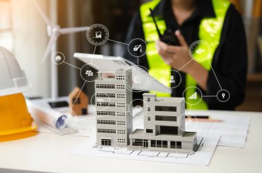 Yaratıcı mimarın orta bölümündeki inşaat simgeleri modern ofisteki masalarda mimari projeler üzerinde çalışıyor