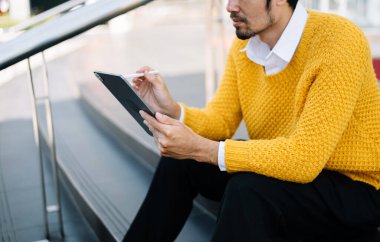 Girişimci şehir caddesinde otururken tablet üzerinde çalışıyor. Tablet taşıyan yakışıklı bir iş adamı ve şehir dışında iş yapıyor.