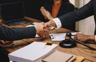 İş adamları ve avukatlar ofiste kontrat belgelerini tartışıyor ve el sıkışıyorlar. Hukuk ve adalet kavramı 