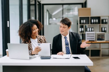 Modern ofiste konuşan ve dizüstü bilgisayar kullanan iki iş adamı.
