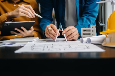 Ofisteki inşaat alanında rüzgar enerjisi konulu mimari projeyi tartışan iki meslektaş