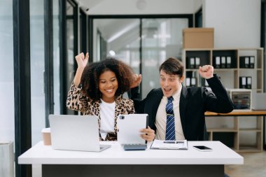 Modern ofiste konuşan ve dizüstü bilgisayar kullanan iki iş adamı.