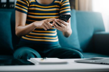 Modern ofisteki iş yerinde akıllı telefon üzerinde çalışan kendine güvenen bir iş kadını.