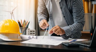 Modern ofisteki inşaat sahasında mimari projeyle büyük çizimlere yansıyan yaratıcı mimar