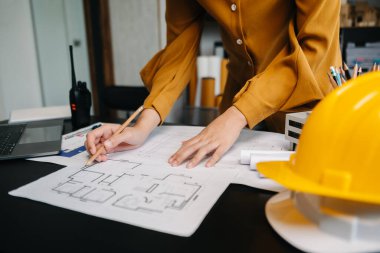 Kadın mimarın orta bölümü, masa başında mimari projeyle çalışıyor. 