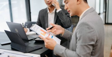 Ofisteki yeni projeyi tartışan ve çalışan meslektaşlar dizüstü bilgisayar ve dijital tablet kullanıyorlar 