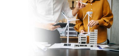 Alternatif enerji mühendisi ve iş arkadaşı modern ofiste geleceğin gücü hakkında tartışıyorlar.