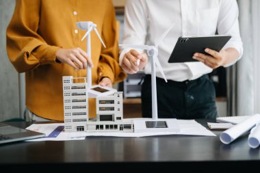 İki mimarın orta bölümü, masadaki mimari projede birlikte çalışıyor.