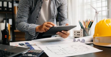 Mimarlığın orta bölümü mimarlık projesinde çalışıyor, masa başında planlar yapıyor. 