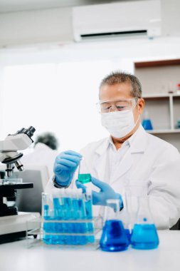 Bir tıp laboratuarında araştırma yapan kıdemli bilim adamları, ön plandaki bir araştırmacı tıp laboratuarında bir mikroskop kullanıyor.. 