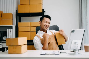 Başlangıçta küçük işletme KOBİ 'si, girişimci sahibi tablet kullanarak paket ürün kutularını hazırlamak için çevrimiçi alışveriş siparişini alır ve kontrol eder 