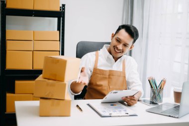 Başlangıçta küçük işletme KOBİ 'si, girişimci sahibi tablet kullanarak paket ürün kutularını hazırlamak için çevrimiçi alışveriş siparişini alır ve kontrol eder 