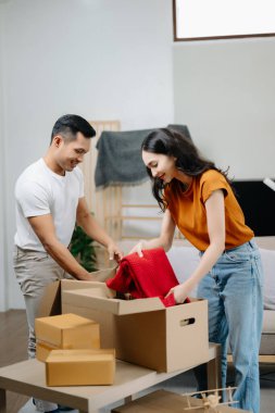 Mutlu Asyalı genç ve çekici çift büyük kutularla yeni bir eve taşınıyor.