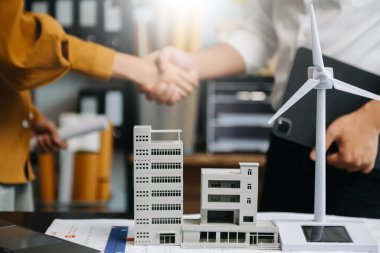 Alternatif enerji mühendisi ve iş arkadaşı modern ofiste geleceğin gücü hakkında tartışıyorlar.