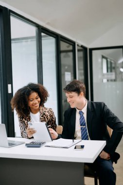 Modern ofiste konuşan ve dizüstü bilgisayar kullanan iki iş adamı.
