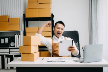 Başlangıçta küçük işletme KOBİ 'si, girişimci sahibi tablet kullanarak paket ürün kutularını hazırlamak için çevrimiçi alışveriş siparişini alır ve kontrol eder 