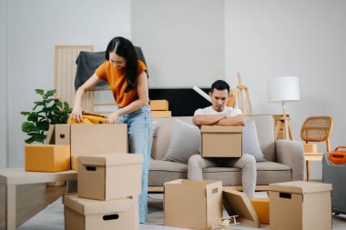 Asyalı genç ve çekici kadın ve erkek yeni eve karton paketle taşınıyorlar. Genç evli Asyalı eve taşınıyor.