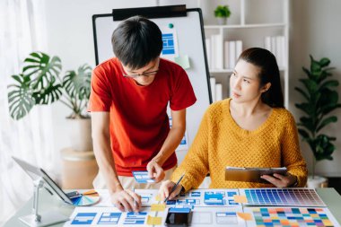  UX geliştiricileri ve ui tasarımcıları modern ofiste müşteri özeti ve renk kodu ile mobil uygulama arayüzü kablo tasarımı hakkında beyin fırtınası yapıyorlar.