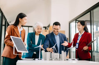 Bir grup alternatif enerji mühendisi, bir iş adamıyla bir projeyi tartışıyor güneş pili paneli ve Güneş Enerjisi Çevre Şehri Konsepti 'nde bir toplantı yapıyor. Ofiste.