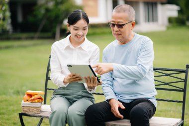 Asyalı yaşlı, kıdemli bir adam ve Asyalı dikkatli bir bakıcı. Sabahları bakımevi bahçesi konsepti
