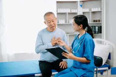 Üniformalı Asyalı doktor, hastanede ya da klinikte salin solüsyonu alan Asyalı yaşlıları ve yatakta yatan hastaları tartışırken not alıyor..