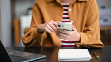 Yeni İş Projesi 'nde çalışan genç kadın muhasebe müdürü. İş kadını ofiste akıllı telefon ve dizüstü bilgisayar kullanıyor. 