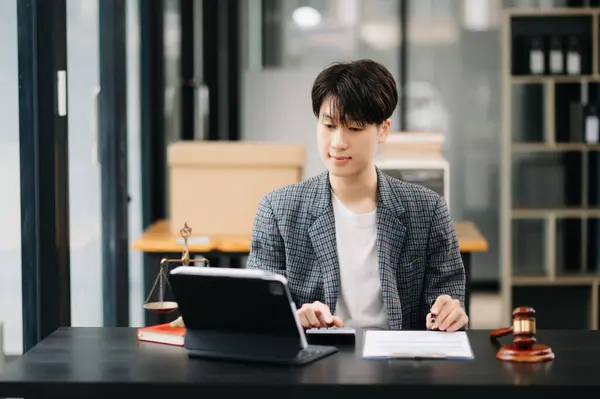 Attractive young lawyer using digital tablet on desk in modern office. Law concept