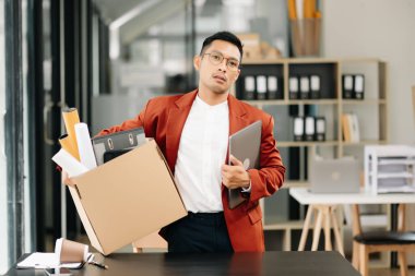 Mutlu ve heyecanlı Asyalı genç ofis çalışanı istifasını kutluyor, kişisel eşyalarını taşıyor. Modern ofisteki işi bırakmak, değiştirmek ya da şirket kurmak