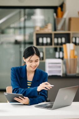 Modern ofiste dizüstü bilgisayarla çalışan Asyalı bir iş kadını. 