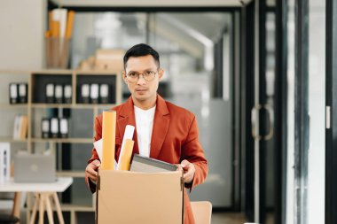 Mutlu ve heyecanlı Asyalı genç ofis çalışanı istifasını kutluyor, kişisel eşyalarını taşıyor. Modern ofisteki işi bırakmak, değiştirmek ya da şirket kurmak