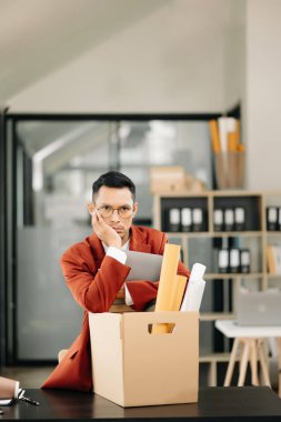 Mutlu ve heyecanlı Asyalı genç ofis çalışanı istifasını kutluyor, kişisel eşyalarını taşıyor. Modern ofisteki işi bırakmak, değiştirmek ya da şirket kurmak