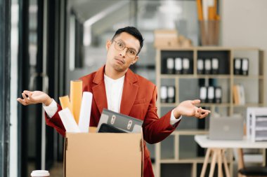 Mutlu ve heyecanlı Asyalı genç ofis çalışanı istifasını kutluyor, kişisel eşyalarını taşıyor. Modern ofisteki işi bırakmak, değiştirmek ya da şirket kurmak