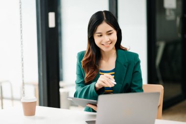 Modern ofiste tablet bilgisayarda çalışan genç ve güzel bir kadın.