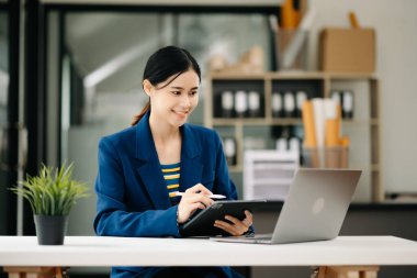 Modern ofiste tablet bilgisayarda çalışan genç ve güzel bir kadın.