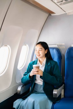Çekici Asyalı kadın yolcu rahat koltukta oturuyor. Şık bir şekilde seyahat et, sabahları zarafetle çalış.