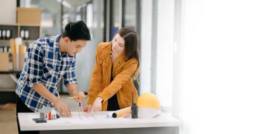 Two colleagues discussing data working with architectural project at construction site at desk in office