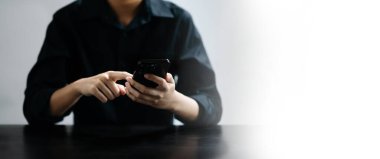 Modern ofisin iş yerinde akıllı telefon üzerinde çalışan kendine güvenen bir işadamı..