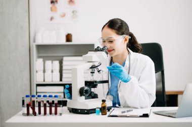 Kadın araştırmacı kimya laboratuvarında bir deney yürütüyor.