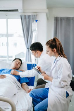 İki doktor, modern hastanede salin solüsyonu alan bir hastayla konuşuyor.