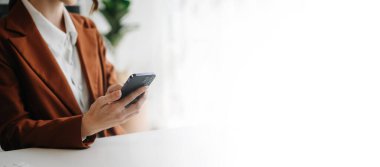 Ofiste sosyal ağ diyagramı olan akıllı telefon kullanan bir iş kadını.