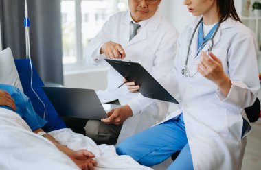 İki doktor hastanede salin solüsyonu alan bir hastayla konuşuyor. 