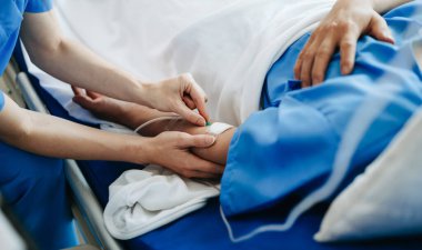 Klinikte ya da hastanede muayene odasında oturan erkek hastayla tedaviyi tartışan doktor.