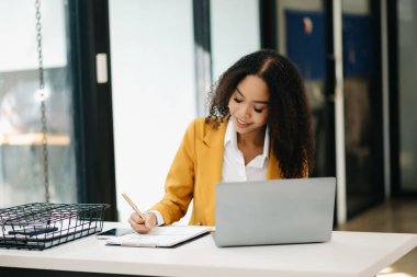 İş kadını ofiste otururken dizüstü bilgisayar kullanıyor.