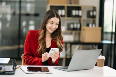Ofiste elinde not defteri ve tabletle gülümseyen kendine güvenen bir kadın.