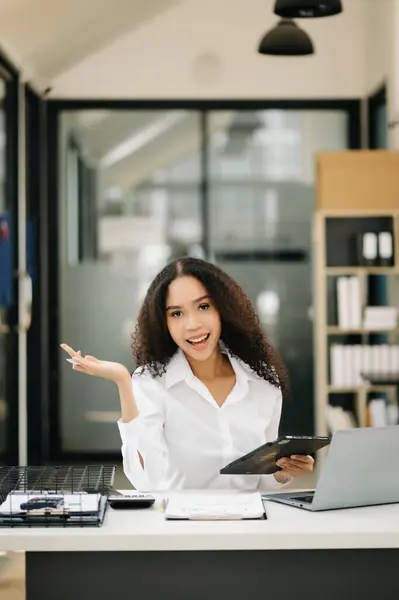 Confident business expert attractive smiling young woman holding digital tablet  on desk in creative office