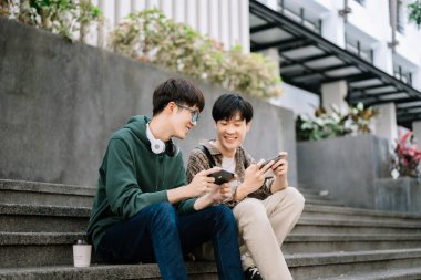 Asyalı öğrenciler kampüs parkını inceliyor. Gençler birlikte vakit geçiriyorlar. Merdivenlerde otururken iletişim kurmak. 