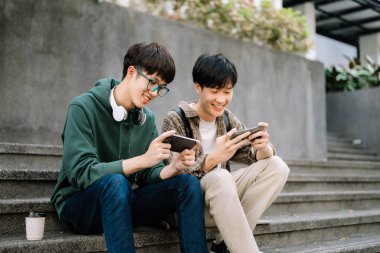 Asyalı öğrenciler kampüs parkını inceliyor. Gençler birlikte vakit geçiriyorlar. Merdivenlerde otururken iletişim kurmak. 