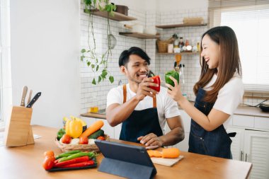 Sabah karısı ona sarılırken mutfakta ekmek ve meyveyle yemek hazırlayan bir adam.